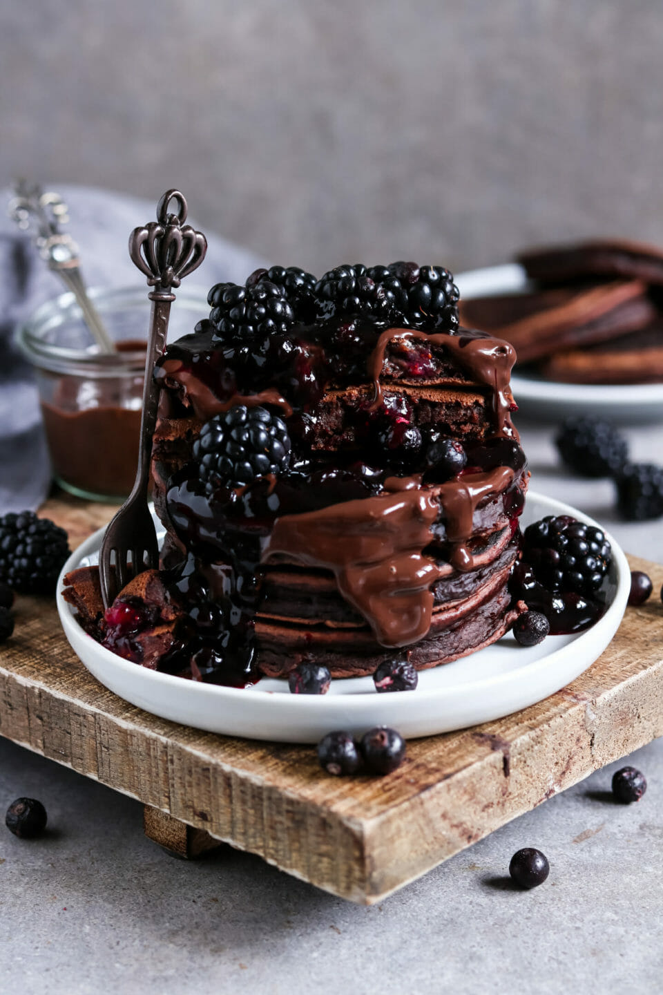 Fluffige Schokoladen Pancakes mit Blaubeeren und Banane serviert mit Schokoladen Sauce, Brombeeren, Beeren Kompott und gefriergetrockneten Beeren