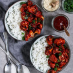 Vegane Blumenkohl Wings serviert mit Reis, Sesam und Lauchzwiebeln.