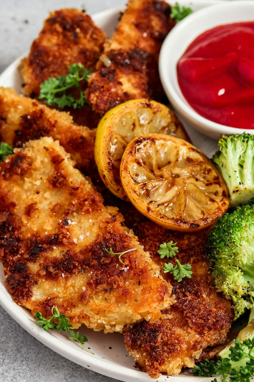 Vegane Schnitzel aus Sellerie. Serviert mit Brokkoli, Zitrone und Ketchup.