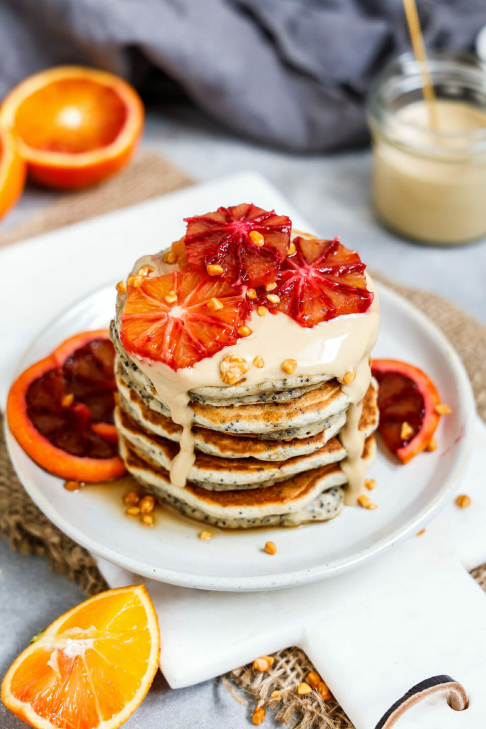 Vegane Orangen Mohn Pancakes aufgeschichtet auf einem hellen Teller und Marmorbrett