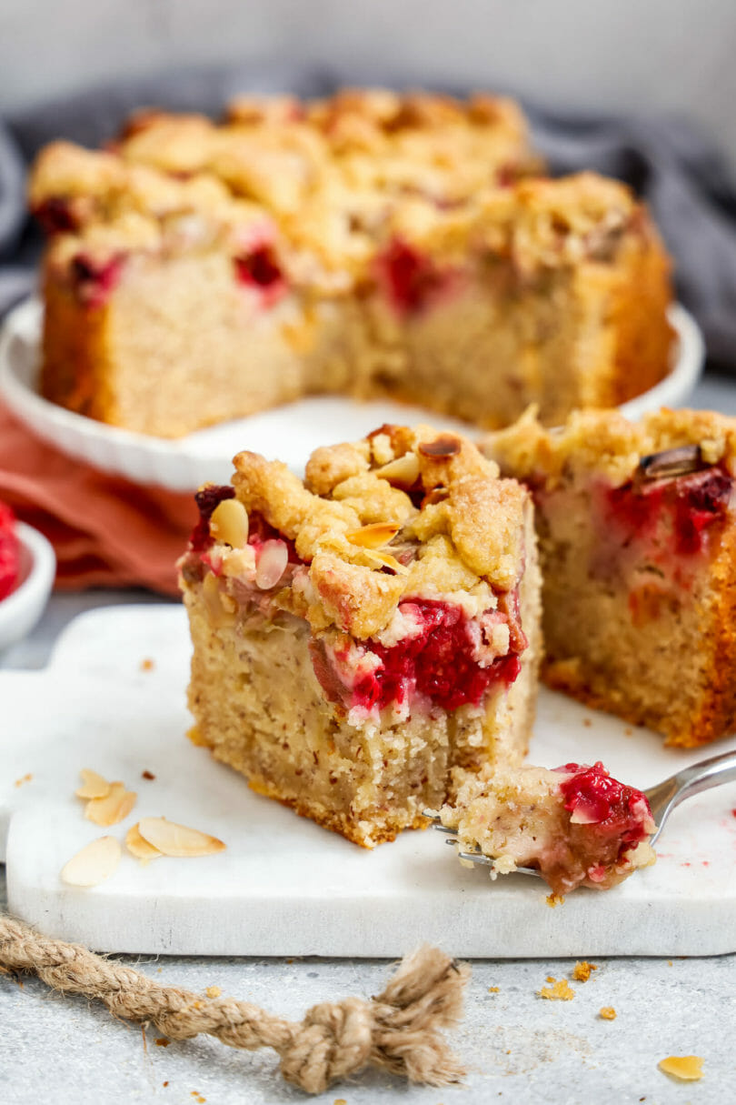 Veganer Rhabarber-Himbeer-Kuchen mit Streusel serviert auf einer hellen Marmorplatte