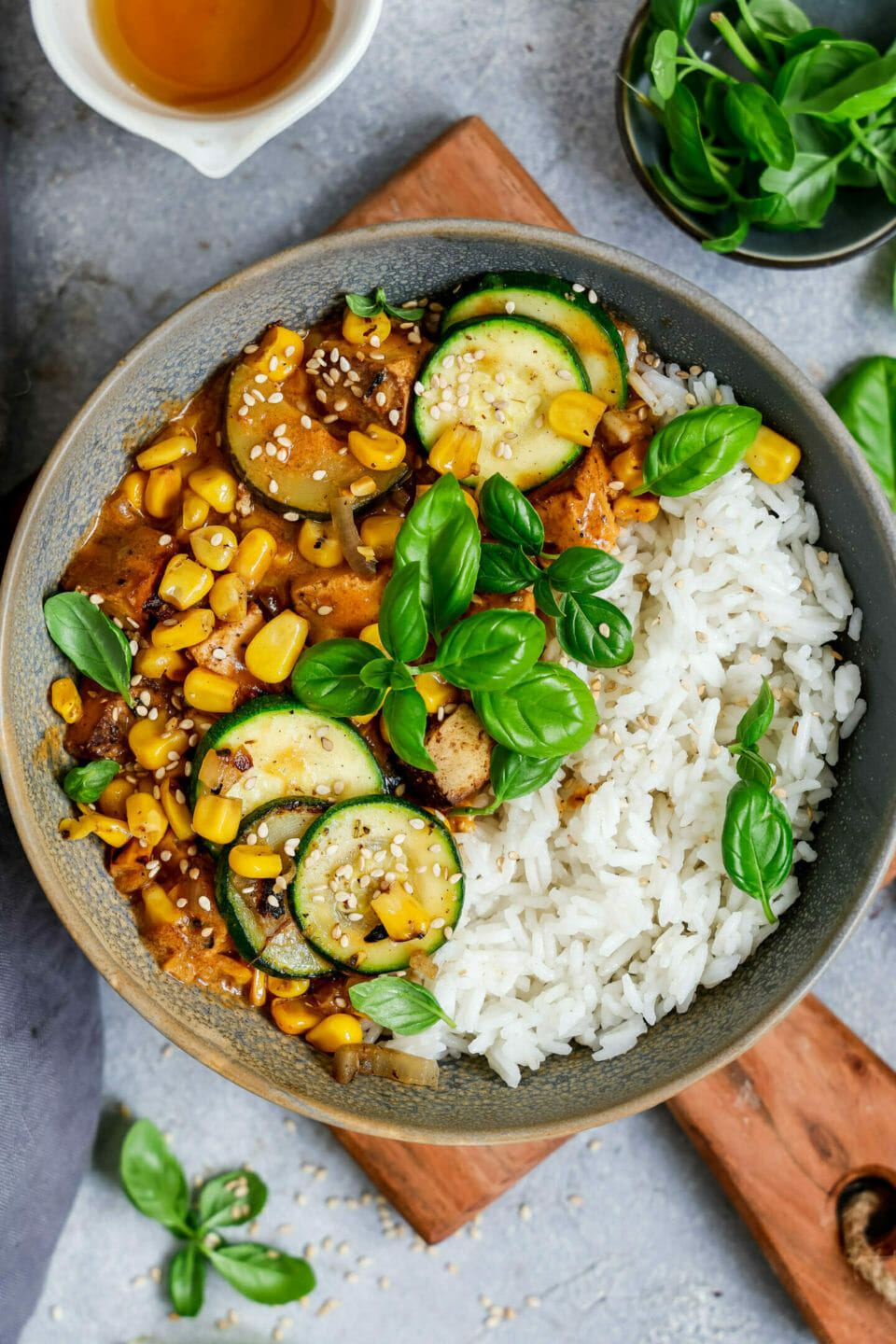 Veganes Kokos Curry angerichtet mit Reis in einer tiefen Schüssel auf einem Holzbrett