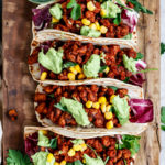 Vegane Tacos, gefüllt und aufgereiht auf einem Holzbrett