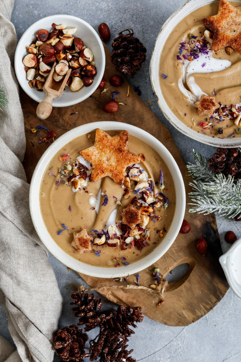 Cremige Maronensuppe mit Zimt-Croûtons weihnachtlich angerichtet und mit geröstetet Haselnüssen sowie Kräutern und Blüten dekoriert