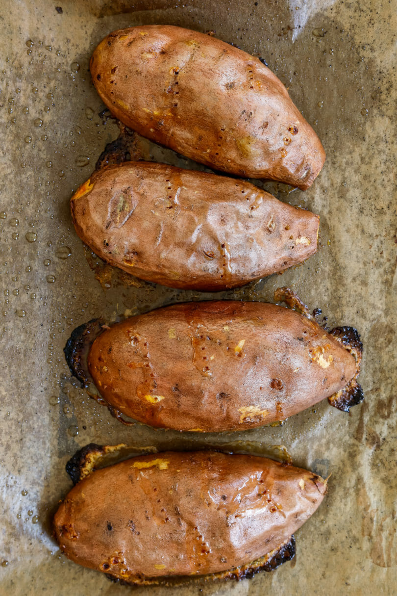 Ofen-Süßkartoffeln auf einem Stück Backpapier - frisch aus dem Backofen - als nächstes werden sie halbiert und mit Füllung bestückt