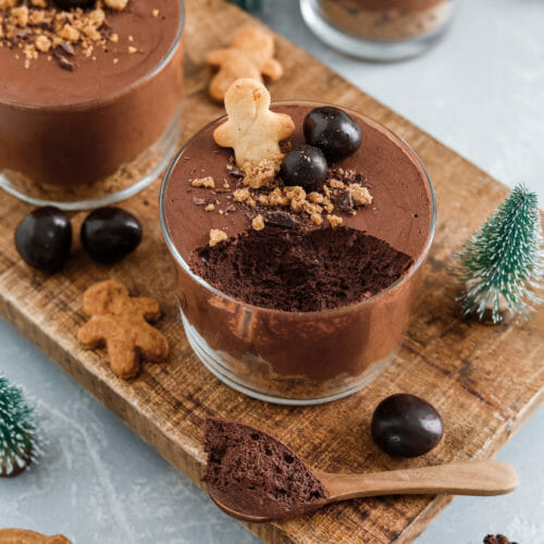 Vegane Mousse au Chocolat mit Weihnachtsdekoration serviert auf einem Holzbrett in kleinen Gläschen