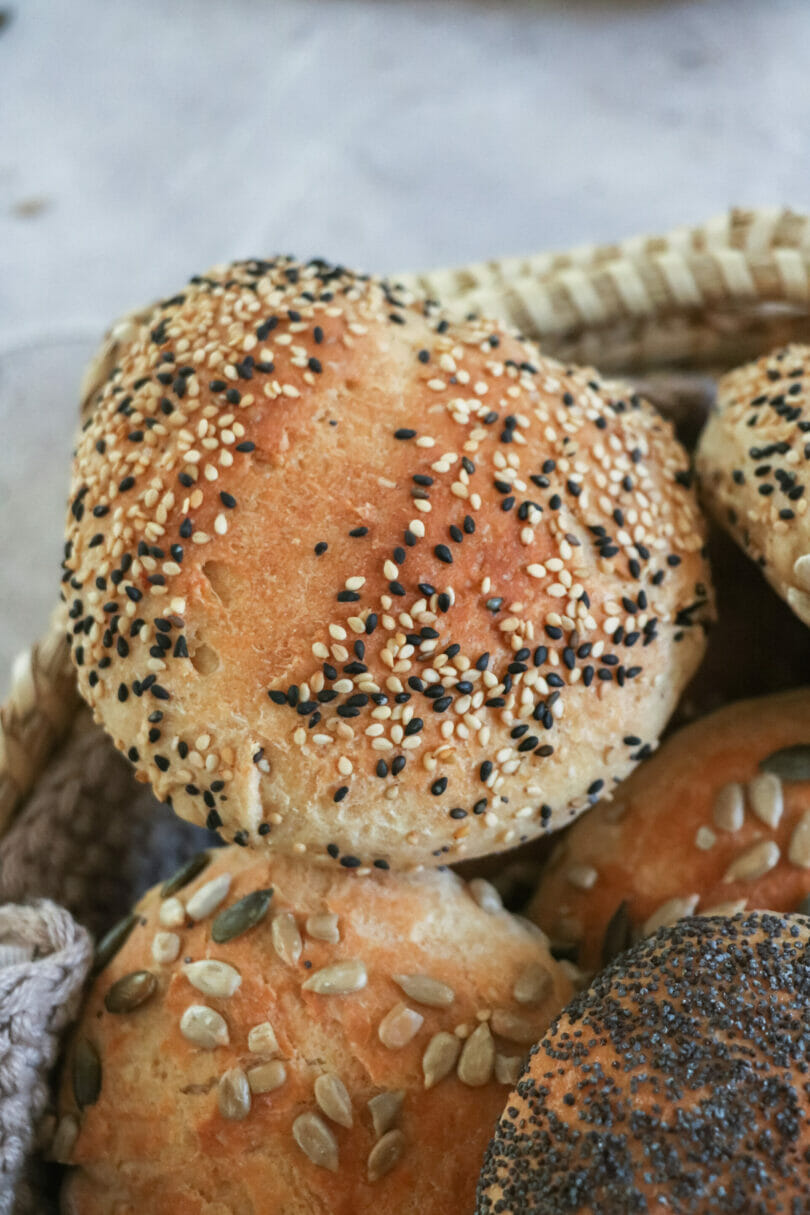 Mehrere goldbraune Brötchen in einem Brotkorb. Darunter Weizen-, Dinkel- und Körnerbrötchen