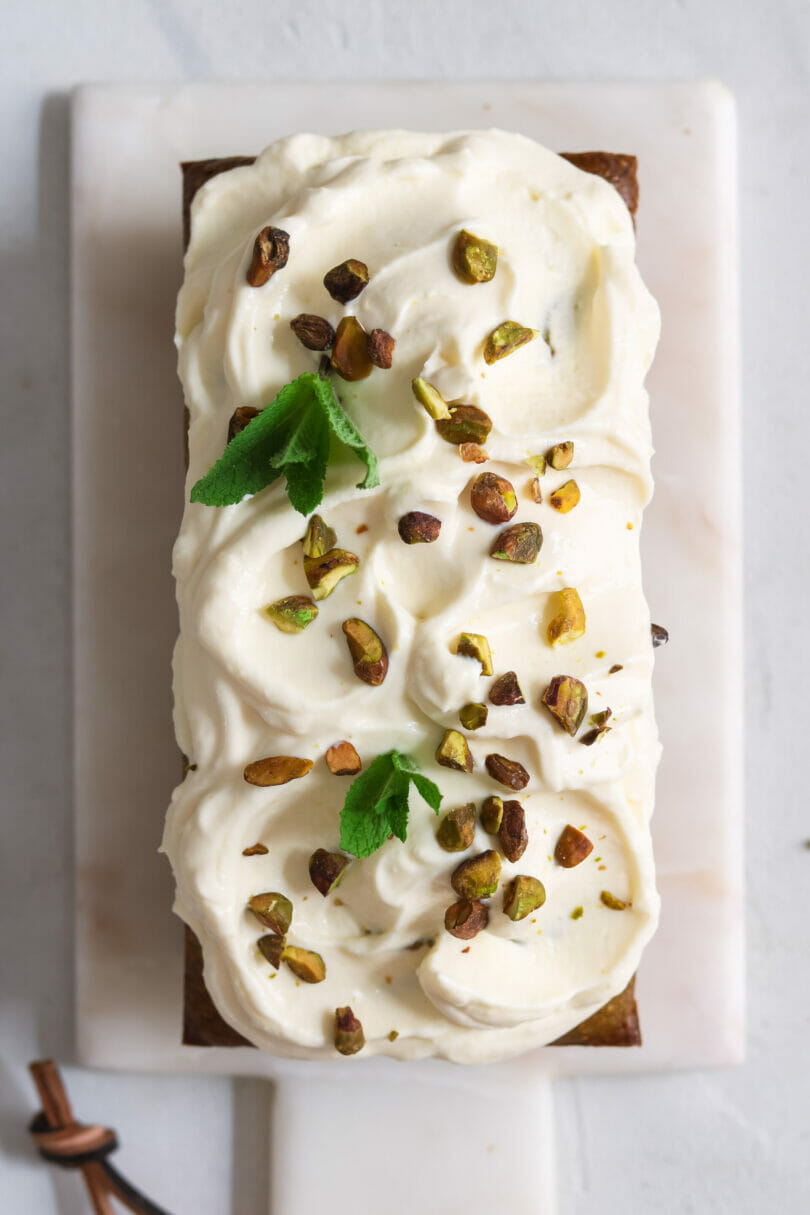 Rezept für veganen Pistazienkuchen mit Zitronenfrosting - auf einem Marmobrettchen und hellem Hintergrund serviert