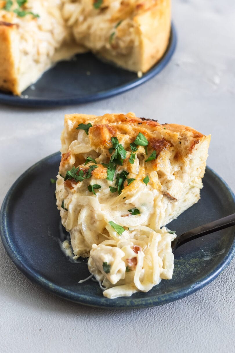Detailaufnahme eines veganen Zwiebelkuchenstücks mit cremiger Füllung, Zwiebeln und frischer Petersilie