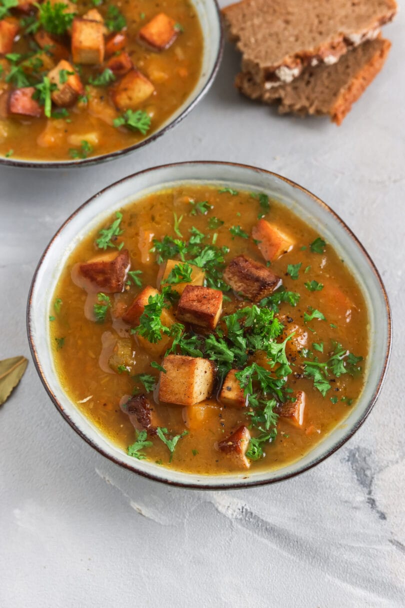 Veganer Steckrübeneintopf mit Räuchertofu in einem tiefen Teller garniert mit Petersilie