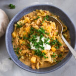Schüssel mit cremigem Wirsingeintopf mit Kartoffelwürfeln und veganem Hack, garniert mit einem Klecks veganen Frischkäse und frischer gehackter Petersilie.