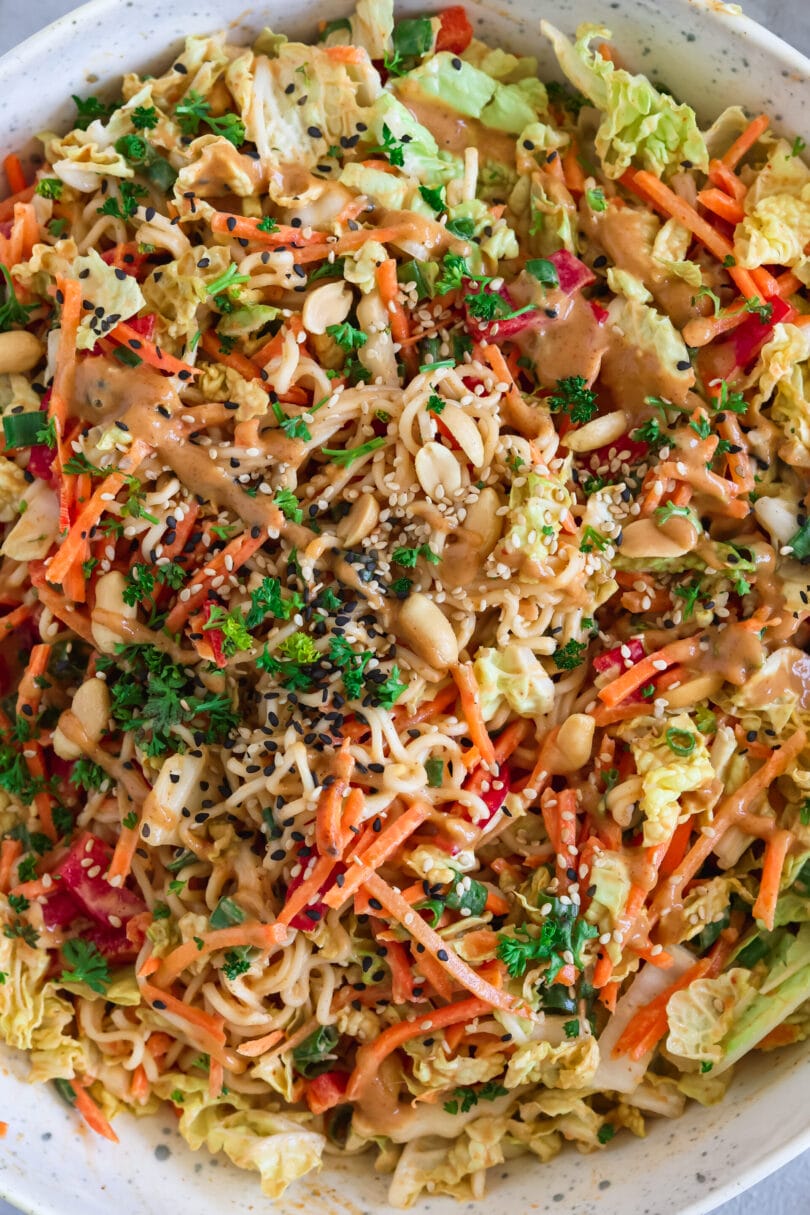 Asiatischer Mienudelsalat mit Chinakohl, Karotten, Paprika, Frühlingszwiebeln und Erdnüssen, serviert mit cremigem Erdnuss-Kokos-Dressing aus Kokosmilch, Sriracha und Sojasauce.