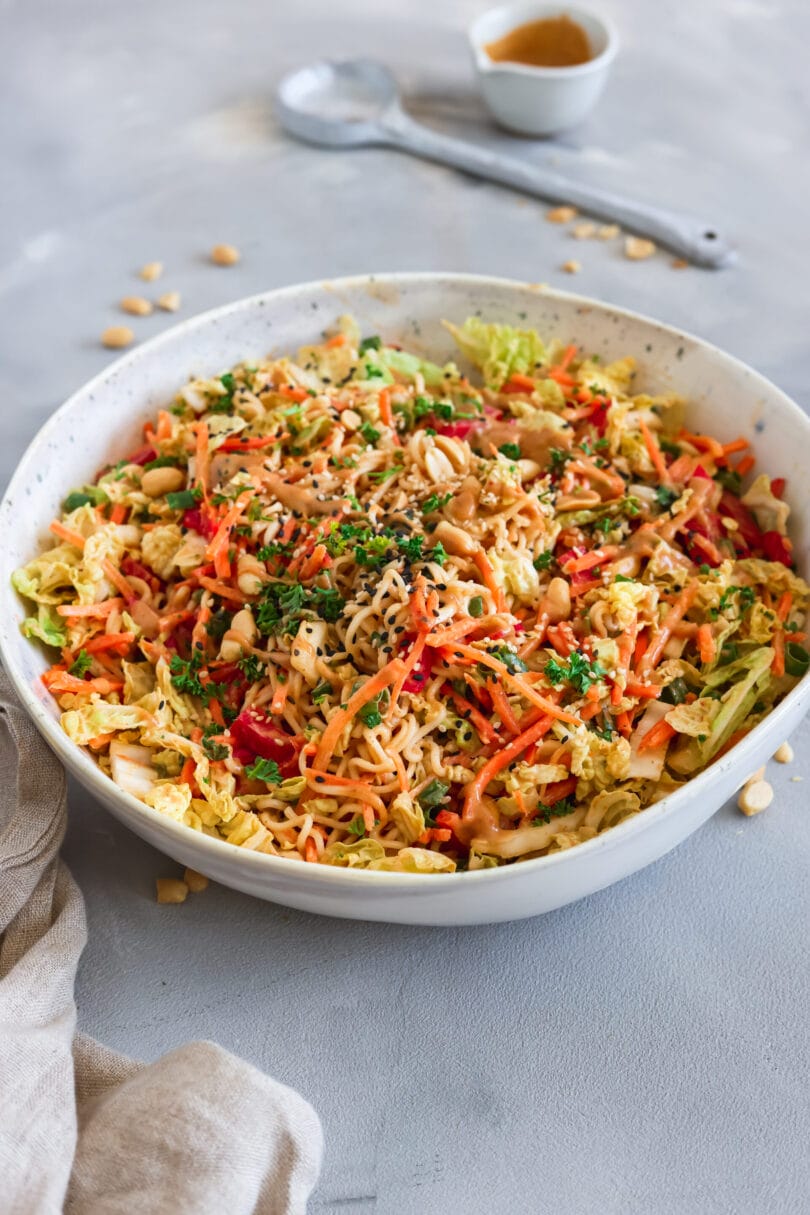 Veganer, chinesischer Nudelsalat mit Mienudeln, Chinakohl, Karotten, Paprika, Frühlingszwiebeln und Erdnüssen in einer Schüssel, verfeinert mit würzigem Erdnuss-Dressing.