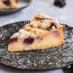 Nahaufnahme eines veganen Brombeerkuchens mit Puddingfüllung, Brombeeren und knusprigen Streuseln.