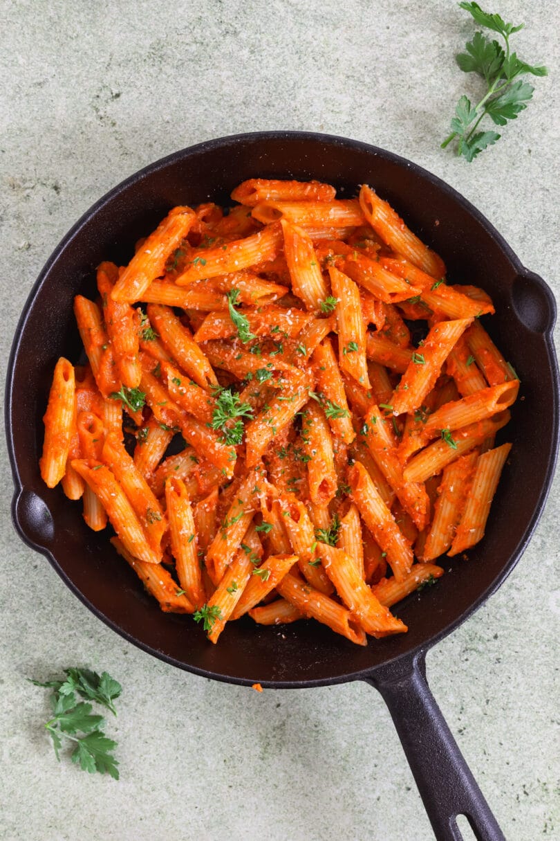 Vegane Penne alla Vodka in einer gusseisernen Pfanne mit cremiger Tomaten-Vodka-Sauce und frischer Petersilie.