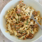 Cremige Pfifferling Pasta mit Bandnudeln in einer hellen Schale, garniert mit Schnittlauch und frisch gemahlenem Pfeffer.