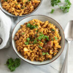 Veganes Steinpilzrisotto mit Pilzstücken und frischer Petersilie in einer Keramikschale.